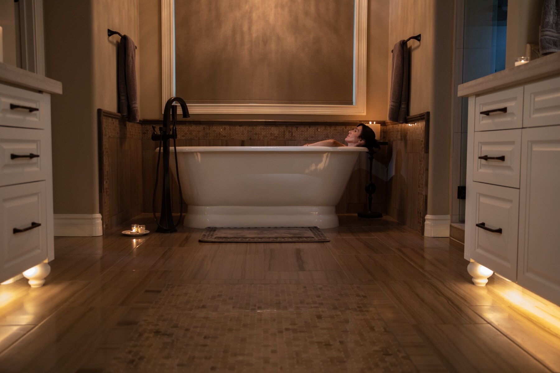 Warm concealed floor and toe-kick accent lighting in a luxury bathroom