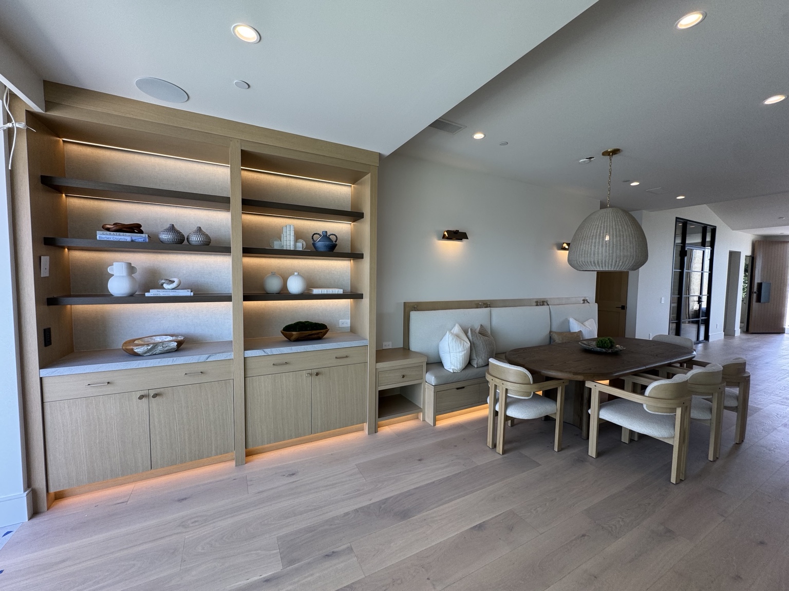 Warm linear lighting integrated into custom dining-room shelving and millwork